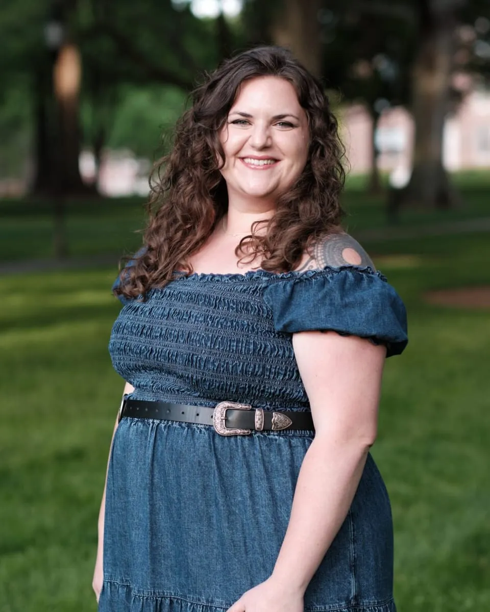 Karrah Wood, founder of Wildflower Psychotherapy & Assessment, smiling outdoors under trees